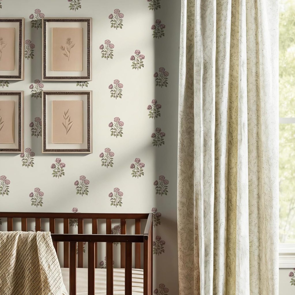 A cozy nursery corner featuring a wooden crib, floral wallpaper with pink and green designs, four framed botanical art pieces, and light curtains beside a window.
