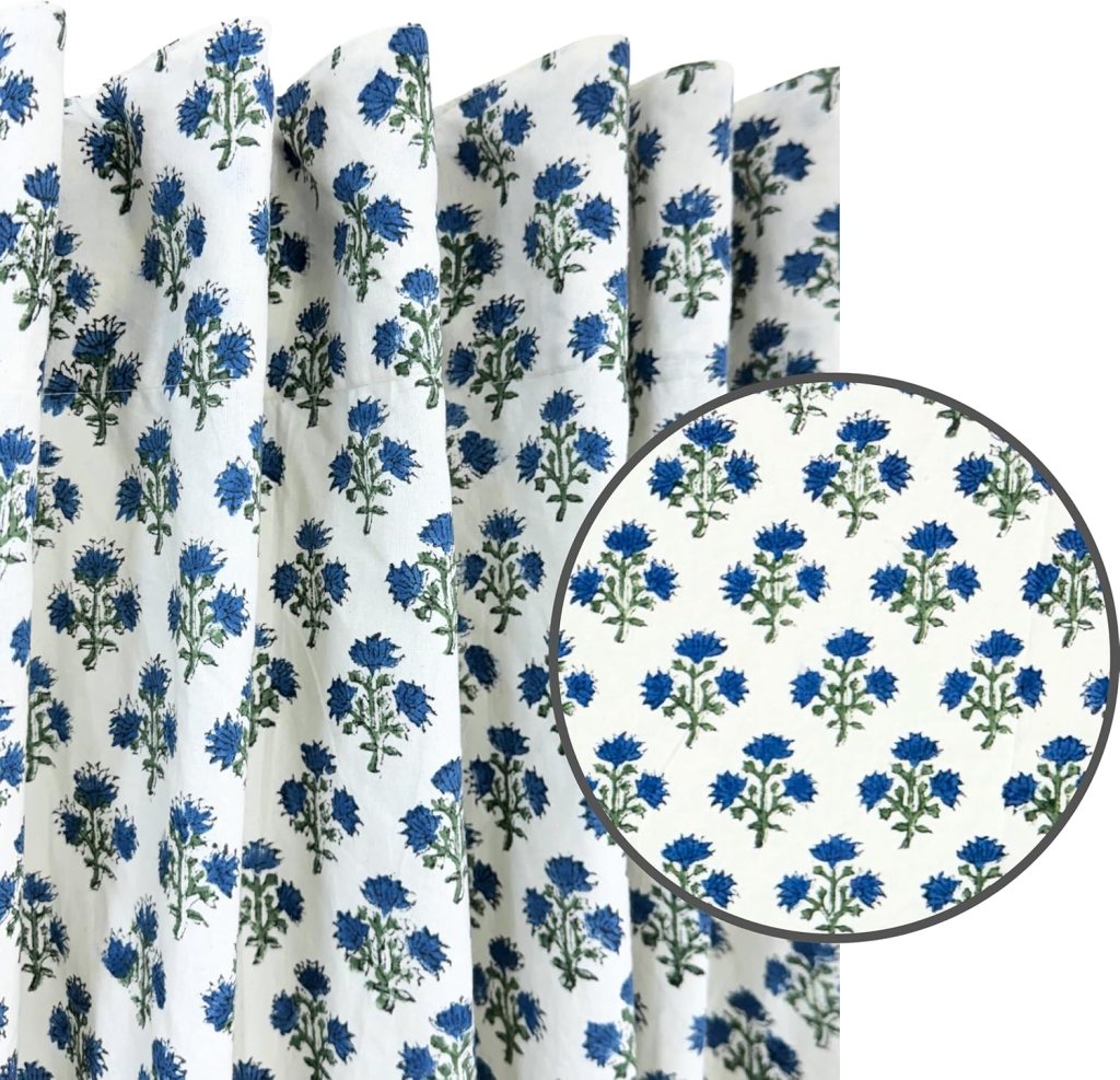 Fabric featuring a floral pattern with blue flowers and green leaves on a white background, displayed in draped folds with a close-up inset.
